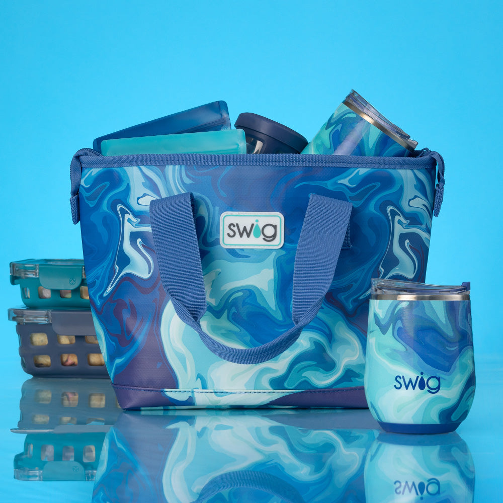 Swig Life Blue Lagoon Lunchi Lunch Bag packed with lunch supplies along with the Blue Lagoon 12oz Wine Cup on a bright blue background