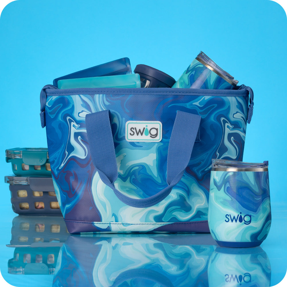 Swig Life Blue Lagoon Lunchi Lunch Bag packed with lunch supplies along with the Blue Lagoon 12oz Wine Cup on a bright blue background
