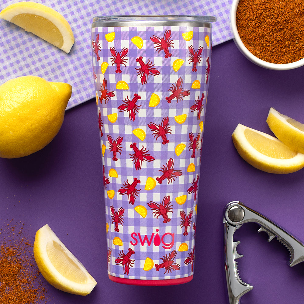Swig Life Let the Good Times Boil 32oz Tumbler with lemons and seasoning shot on a purple background
