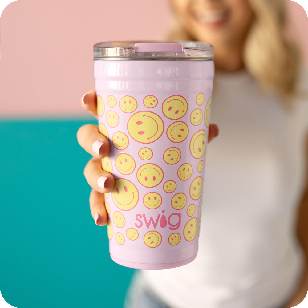 Swig Life 24oz Oh Happy Day Insulated Party Cup being held by a women on a pink background