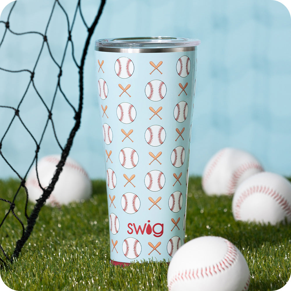 Swig Life 32oz Home Run Insulated Tumbler surrounded by baseballs on a grassy field