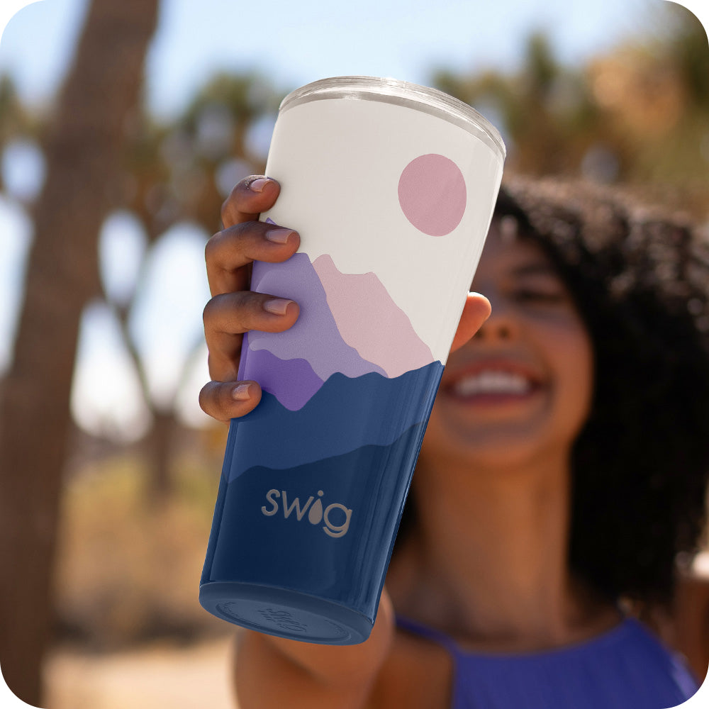 Swig Life 32oz Moon Shine Insulated Tumbler being held by a woman in a blue dress smiling