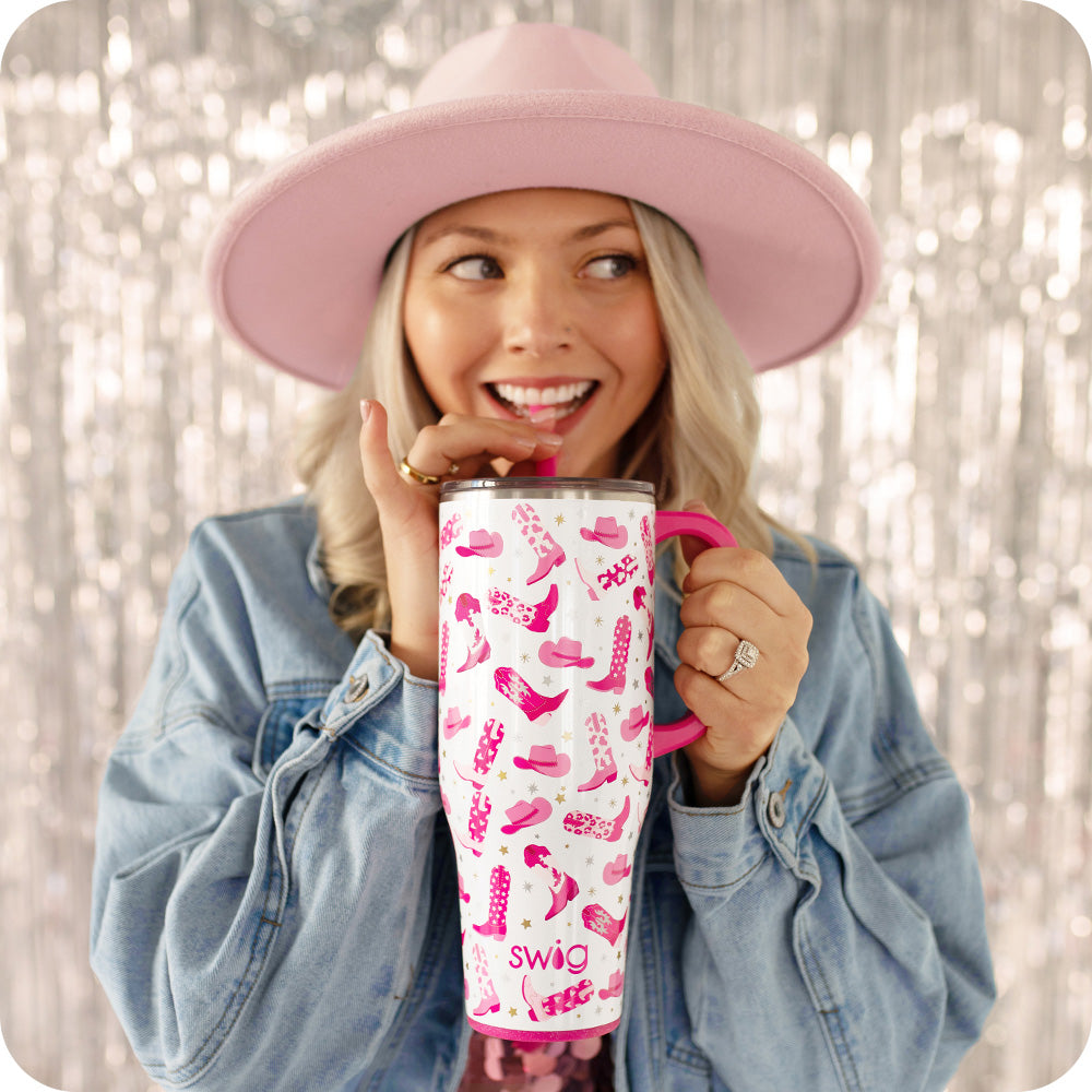Swig Life 40oz Let's Go Girls Insulated Mega Mug being held by a women over a tinsel background