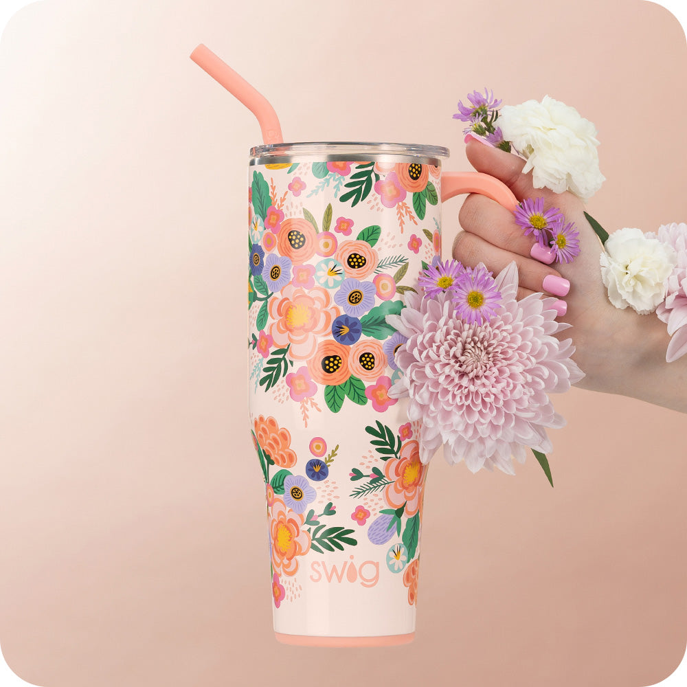 Swig Life 40oz Full Bloom Insulated Mega Mug being held with flowers over a light pink background