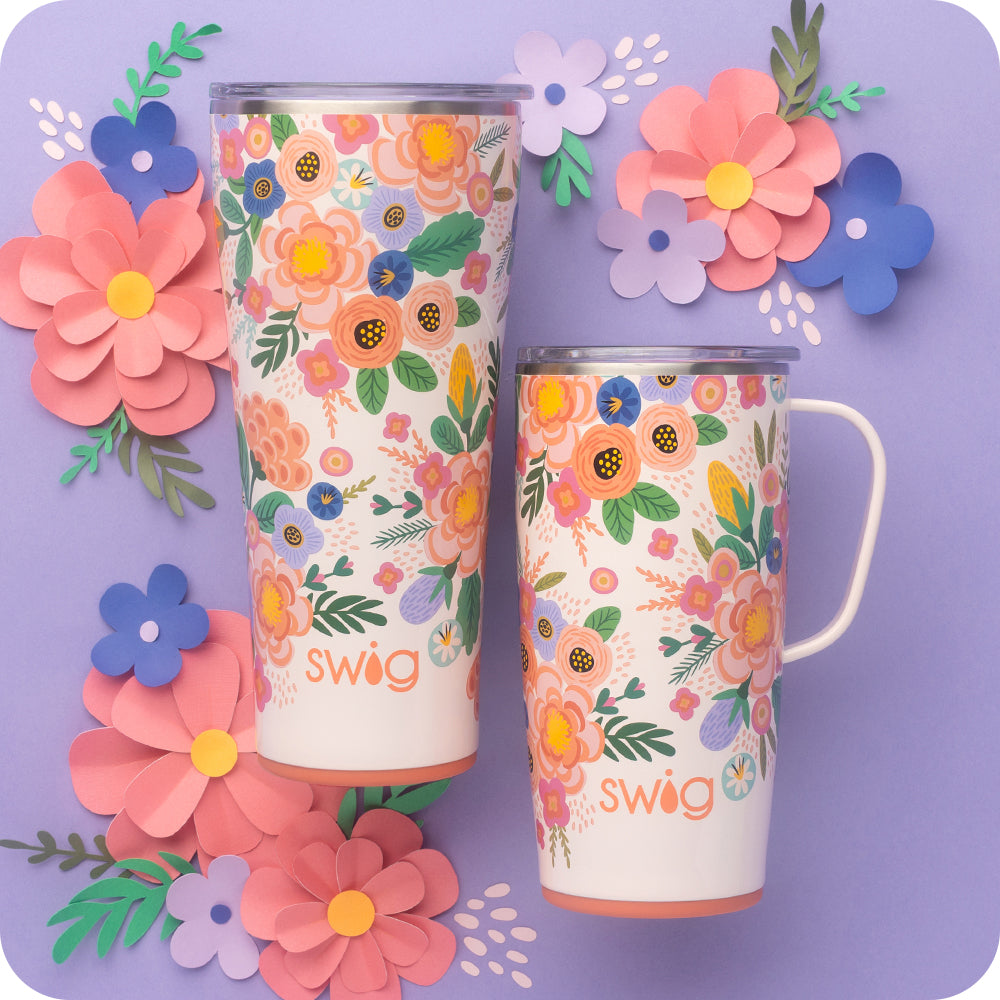 Swig Life Full Bloom 22oz Travel Mug and 32oz Tumbler with colorful paper flowers on a purple background