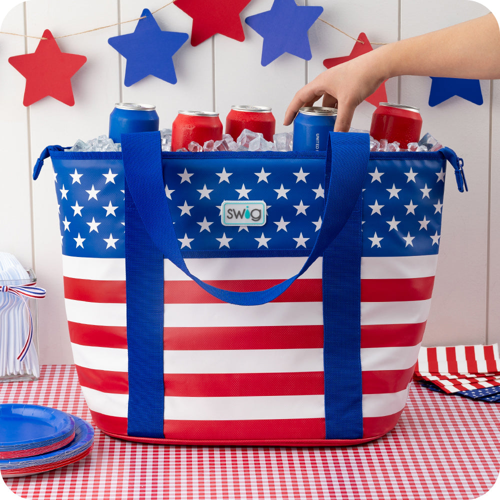 Swig Life All American Insulated Zippi Cooler filled with ice and cans on a red and white gingham tablecloth