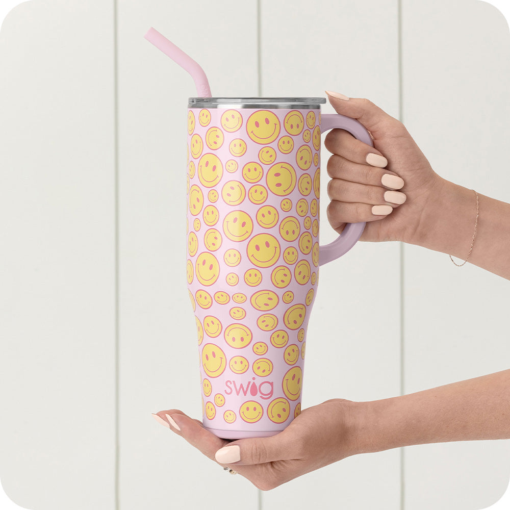 Swig Life 40oz Oh Happy Day Mega Mug shown on a pink background next to small yellow smiley face balls