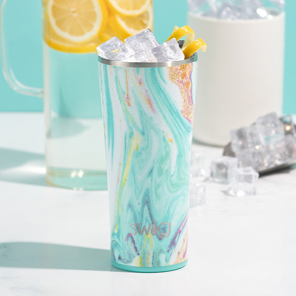 Swig Life 22oz Wanderlust Insulated Tumbler on a white background with a pitcher of lemon water
