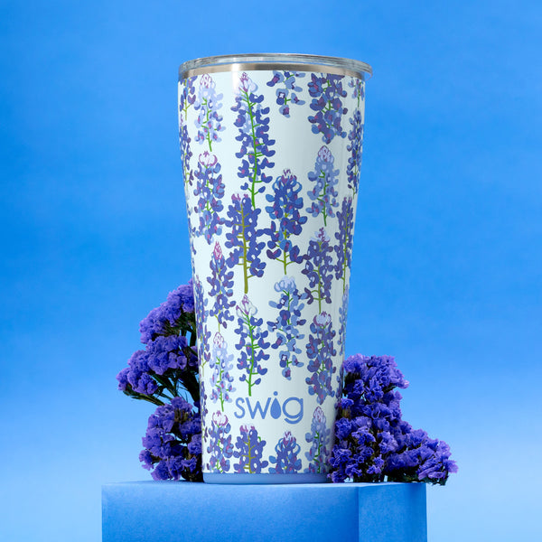 Swig Life 32oz Bluebonnet Insulated Tumbler on a blue background with flowers