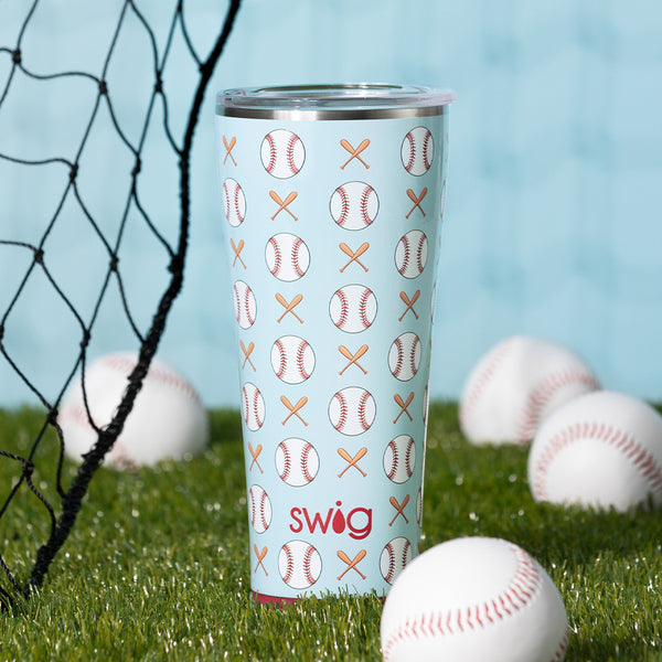 Swig Life 32oz Home Run Insulated Tumbler surrounded by baseballs on a grassy field