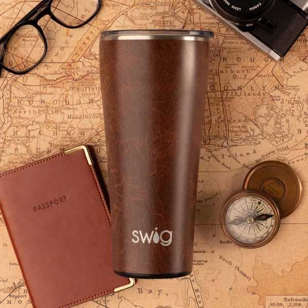 Swig Life 32oz Leather Insulated Tumbler on a brown world map and passport