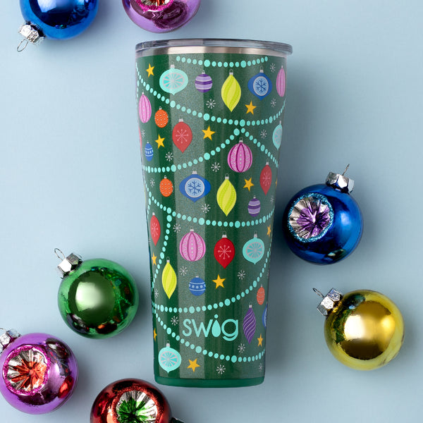 Swig Life 32oz O Christmas Tree Tumbler over a light blue background with colorful Christmas ornaments