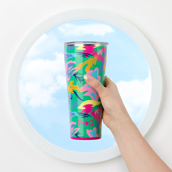 Swig Life 32oz Paradise Insulated Tumbler being held over a round window with the blue sky in the background