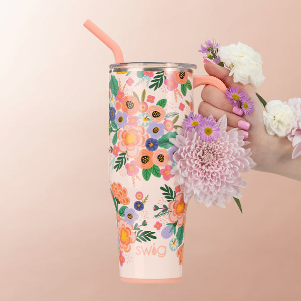 Swig Life 40oz Full Bloom Insulated Mega Mug being held with flowers over a light pink background