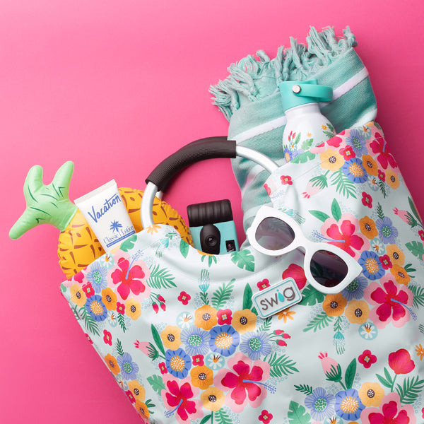 Swig Life Island Bloom Loopi Tote Back filled with travel essentials on a hot pink background