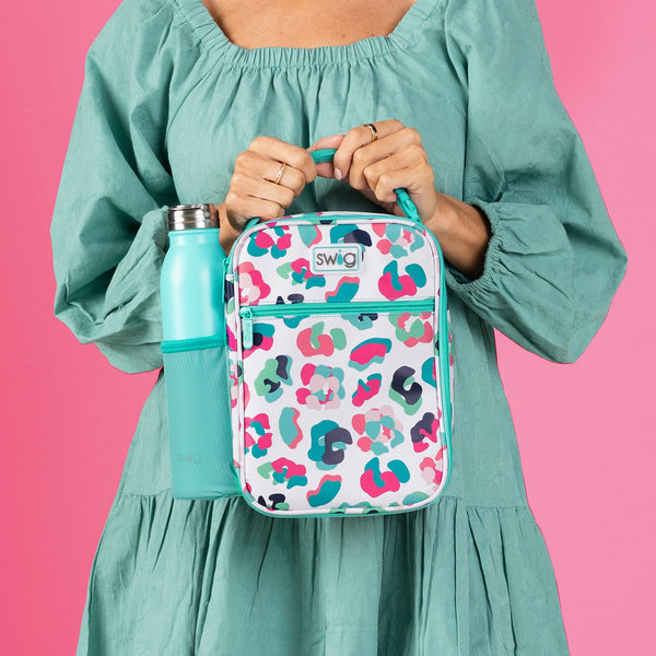 Woman wearing an aqua dress holding Swig Life Party Animal Boxxi Lunch Bag