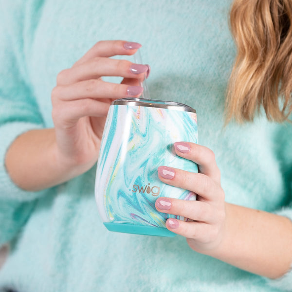 Woman in a light blue sweater holding Swig Life 14oz Wanderlust Stemless Wine Cup