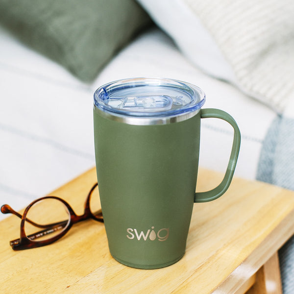 Swig Life 18oz Olive Travel Mug placed on a wooden nighstand