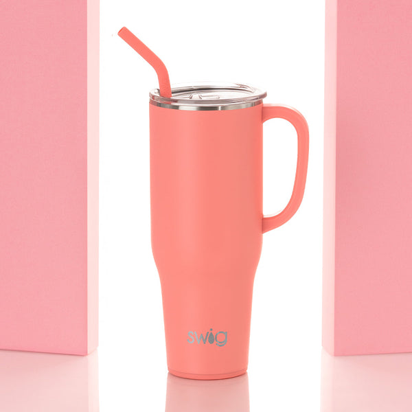 Swig Life 40oz Coral Insulated Mega Mug with lid and handle between two pink pillars