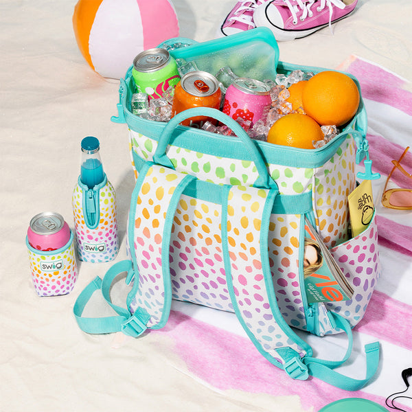 Swig Life Wild Child Packi Backpack Cooler shown with ice and canned beverages inside on a beach setting